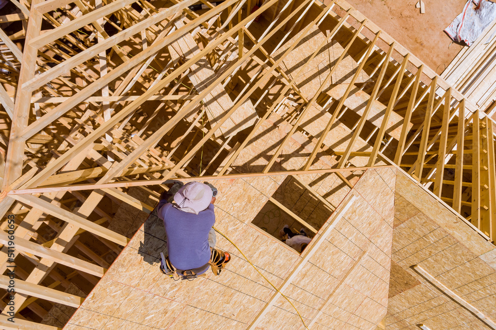 Construction working on the nailing plywood roof sheathing of a new