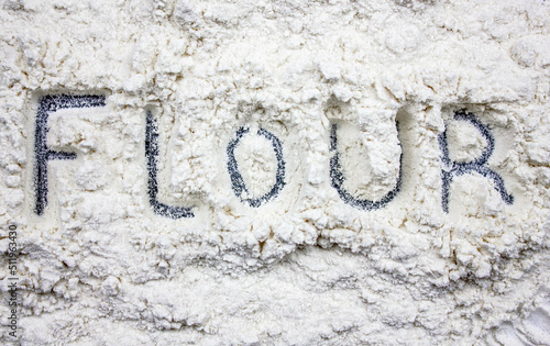 A pile of flour spilled with the word FLOUR. The concept of flour on the table.