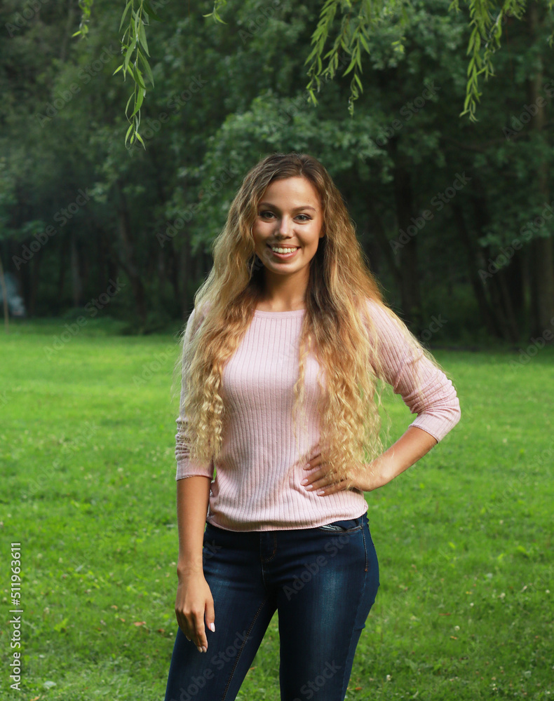 Young beautiful woman with long blond wavy hair. Summer day. Portrait in the park. Young beautiful woman with long blond wavy hair. Summer day. Portrait in the park.