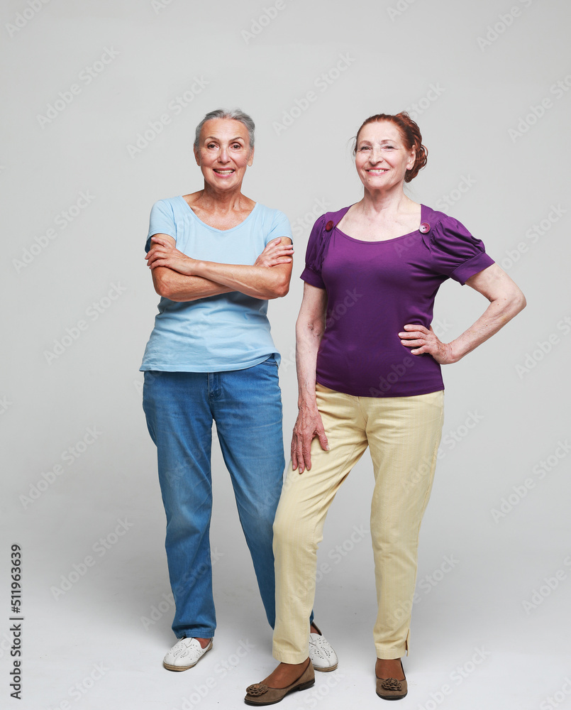 Two pretty older women friends on grey background. Two pretty older women friends on grey background.