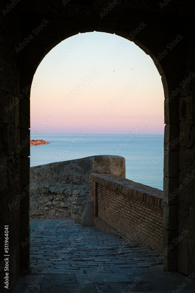 Sunset seen through the arch of Santa Barbara castle, Alicante, Spain.