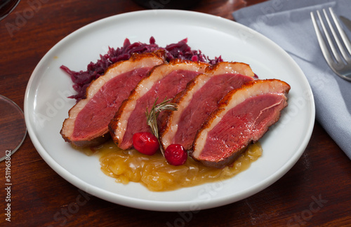 Tasty fried duck breast Magre served with prepared cabbage and caramelized onions at plate