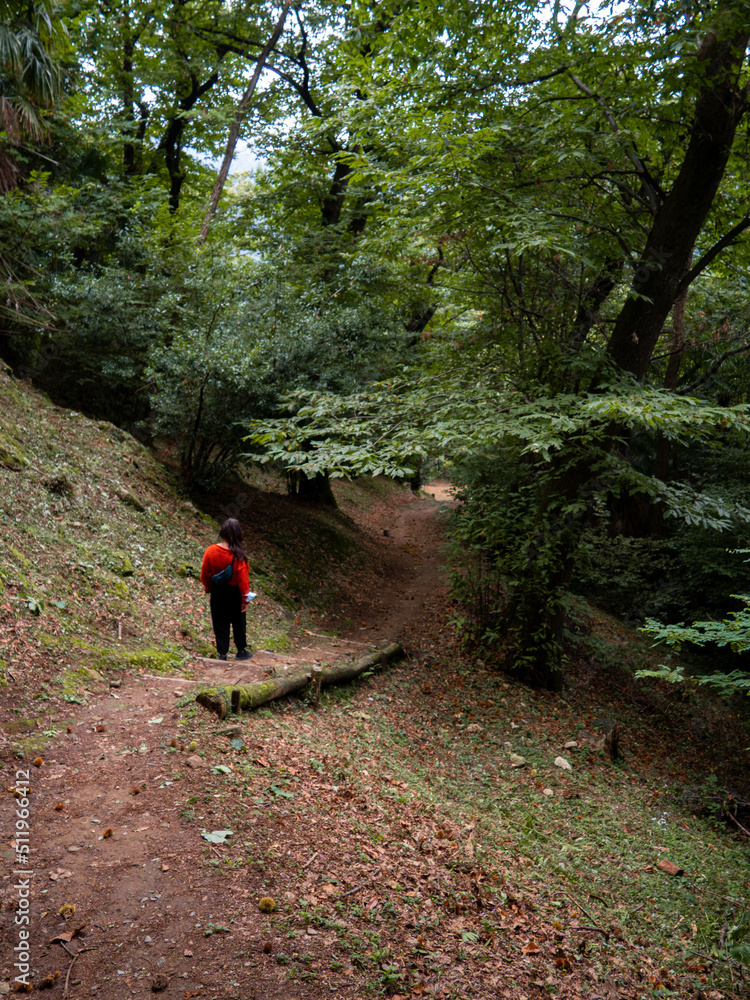 Woman in red shirt exploring the woods alone in como, italia