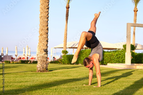 Young Girl Practicing Yoga On Beach At Sunset, Beautiful Woman Summer Vacation Meditation Seaside Sea Ocean Holiday TravelCaucasian woman with yoga posture on the beach at sunset. 