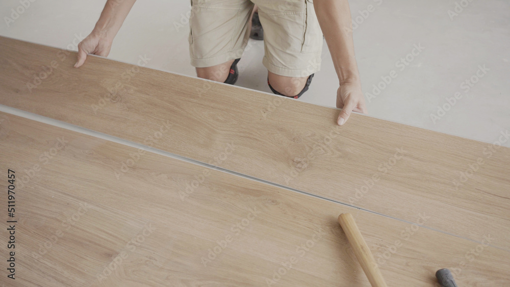 Man installing new timber laminated wooden floor, home improvement, house renovation project concept