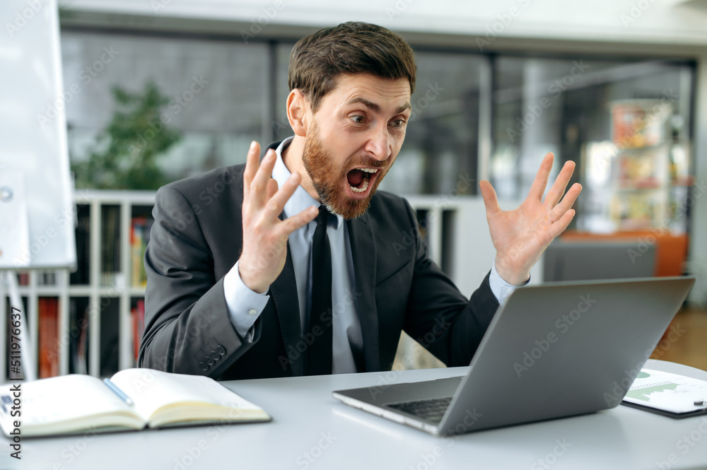 Irritated shocked caucasian male, office worker, product manager, annoyed yelling at a laptop during work, sit in a modern office, in business attire, frustrated by the disruption of an important deal Irritated shocked caucasian male, office worker, product manager, annoyed yelling at a laptop during work, sit in a modern office, in business attire, frustrated by the disruption of an important deal
