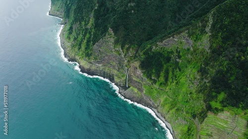 Elevated drone view of cascading waterfall on rocky shoreline; Madeira photo