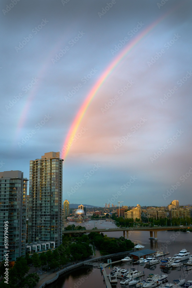 Obraz premium False Creek Rainbow. A rainbow across False Creek at dusk over the Cambie Bridge and towers in Vancouver. British Columbia, Canada.