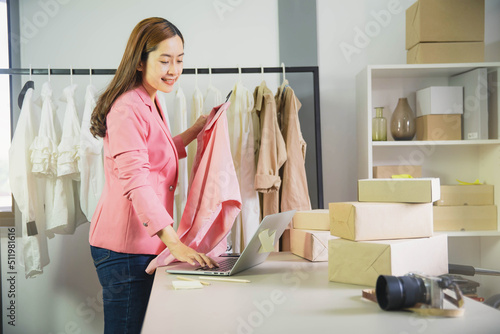Young business woman working online e-commerce shopping at her shop. Young woman seller prepare parcel box of product for deliver to customer. Online selling, e-commerce.