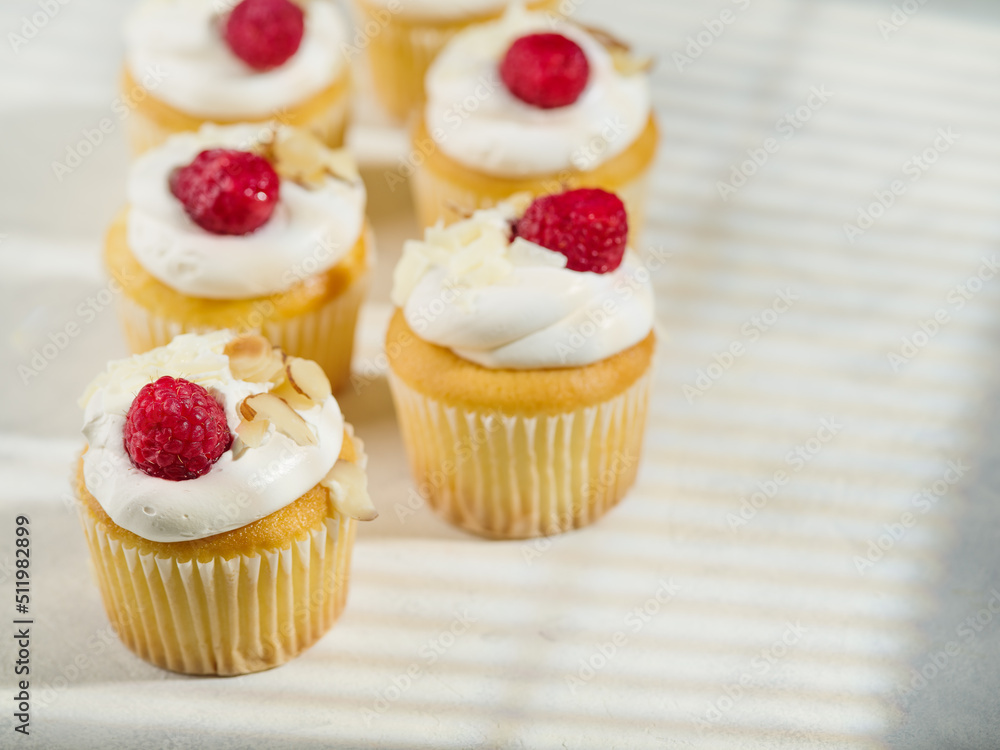 Appetizing muffins with cream and raspberries. Isolated on white background. Sweet food, lots of calories. Holiday, birthday. Restaurant, hotel, cafe, confectionery, catering, banquet, picnic.
