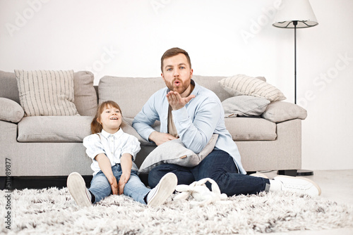 Girl with Down syndrome and her father sitting on a floor and talkiing together photo