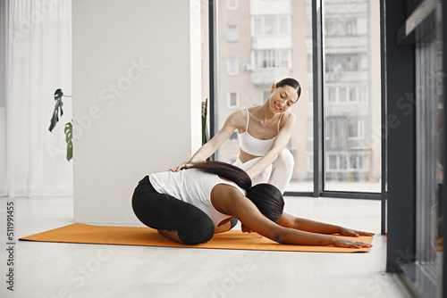 Black woman and caucasian female coach working out in studio with big windows