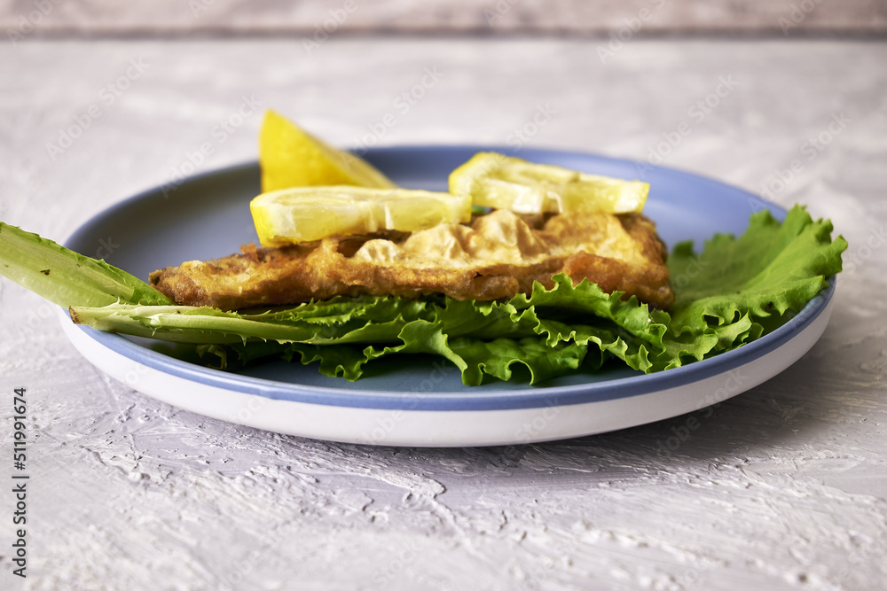 fried fish with lemon and herbs on a plate on the table fried fish with lemon and herbs on a plate on the table