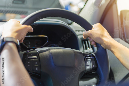 Human hand on the steering wheel drive car with buttons on the steering wheel for phone functions and control