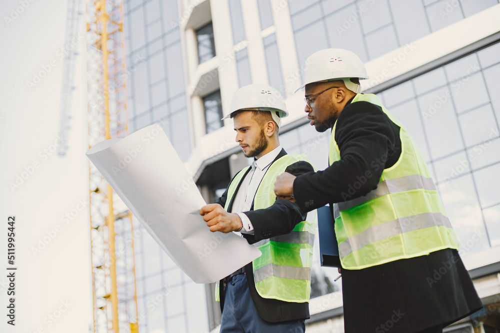 Black man and european looking at blueprint outside Black man and european looking at blueprint outside