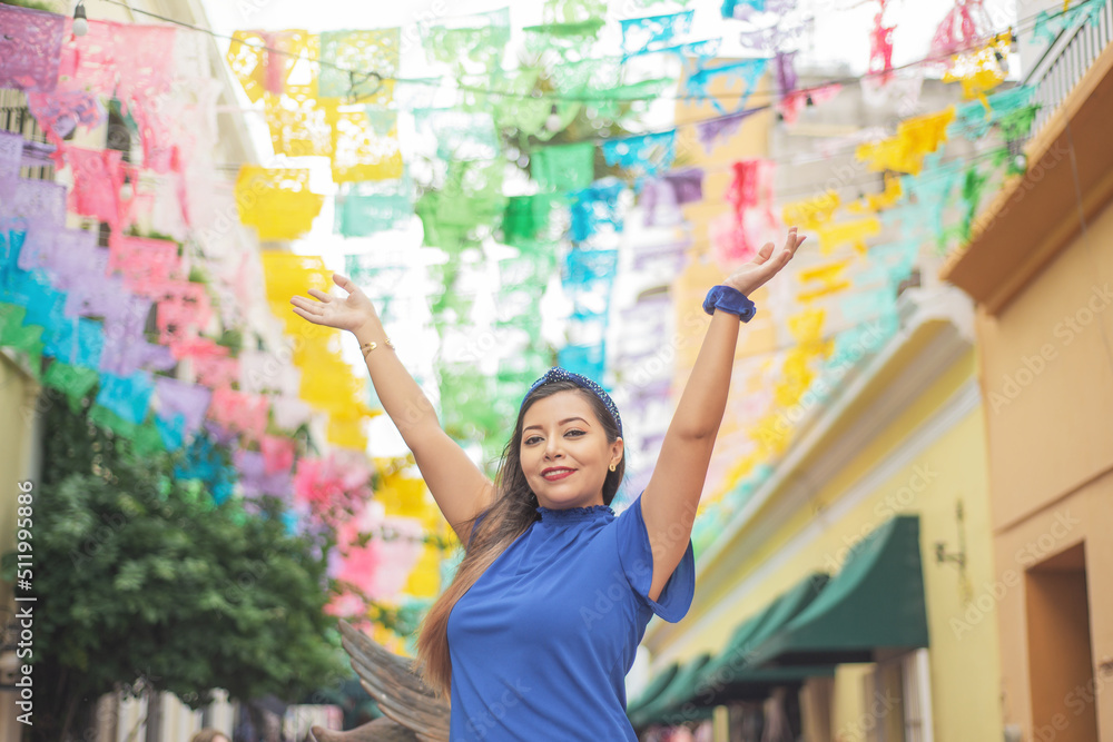 Portrait of woman raising her arms with multicolored flags in the background.