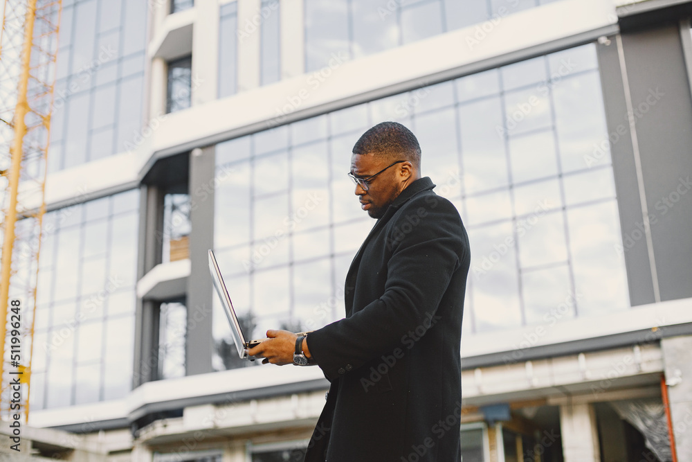 Black race businessman with laptop standing in the city