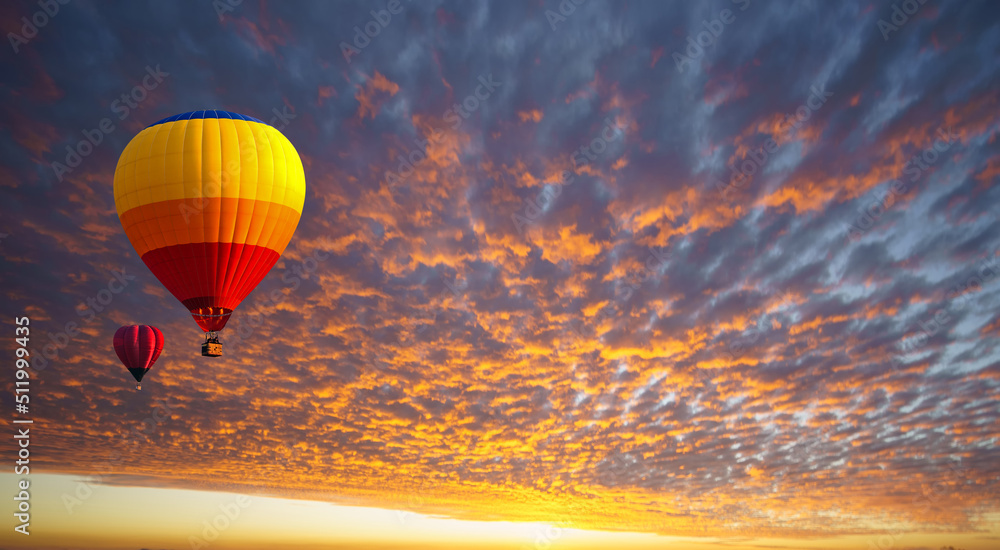 Obraz premium Hot air balloon floating in orange clouds like a sea of fire in the morning before sunrise. Balloons for sports and relaxation, recreation.