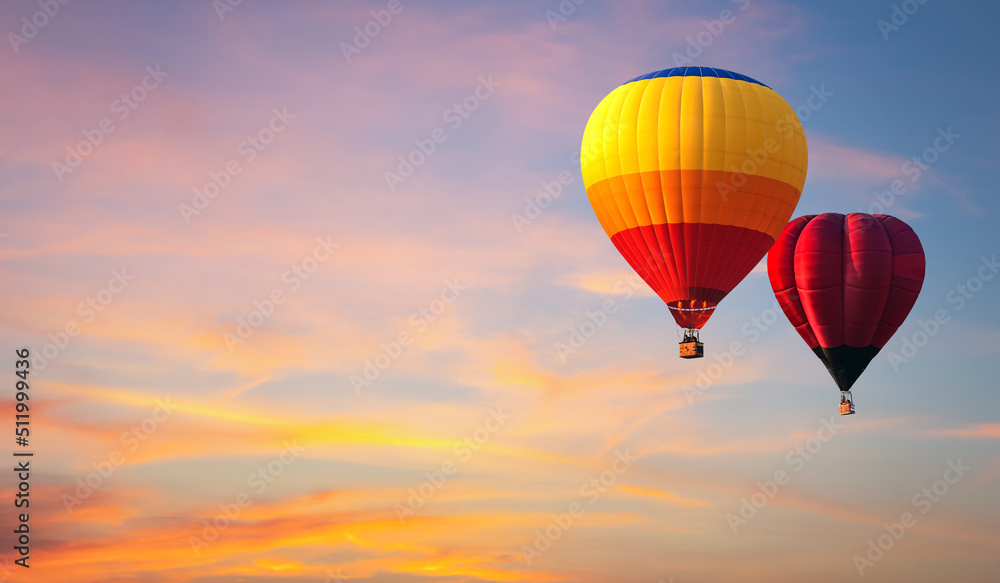 Obraz premium Hot air balloon floating in vivid sky with cloud painted by the sun before sunset in winter. Colorful sky on evening time. Bright blue, orange and yellow colors sunset .