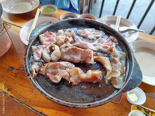 Grilled bacon on a hot pan, on a wooden table