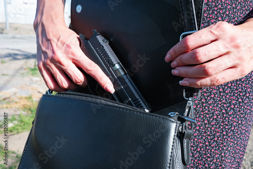 Obraz na plátně Woman with concealed weapon gun in her black small handbag