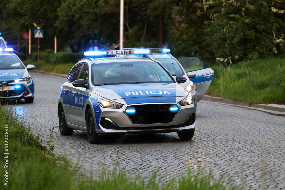Samochód polskiej policji drogowej na sygnałach w mieście alarmowo.  - obrazy, fototapety, plakaty 
