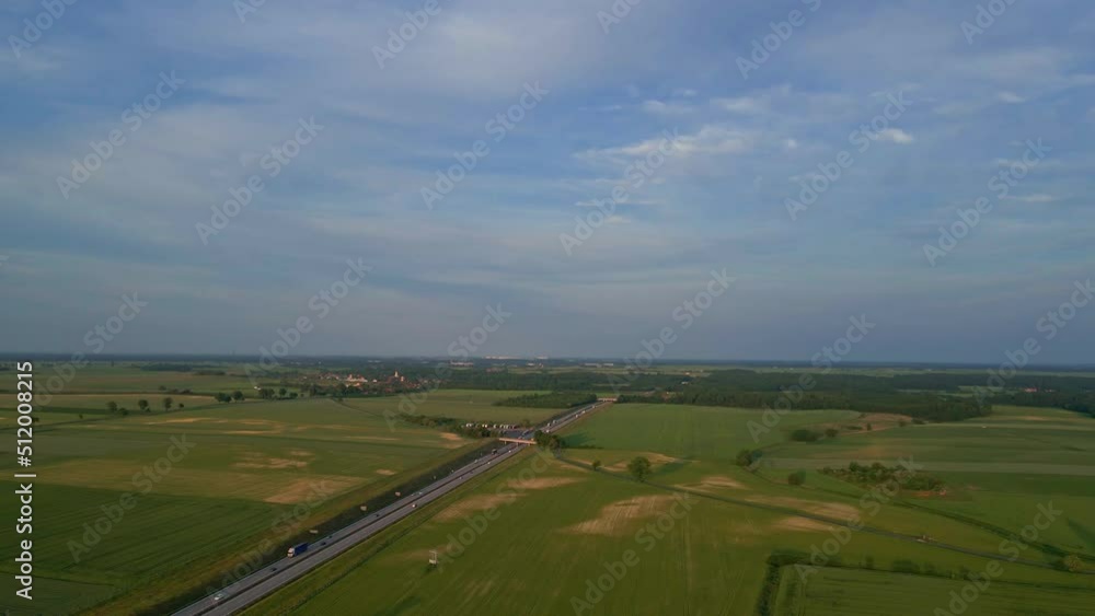 Highway road with car traffic among countryside with agricultural fields at sunset, aerial view Highway road with car traffic among countryside with agricultural fields at sunset, aerial view