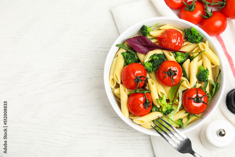 Bowl of delicious pasta with tomatoes, arugula and broccoli on white wooden table, flat lay. Space for text