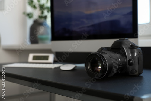 Professional camera and computer on table in photo studio, space for text. Interior design