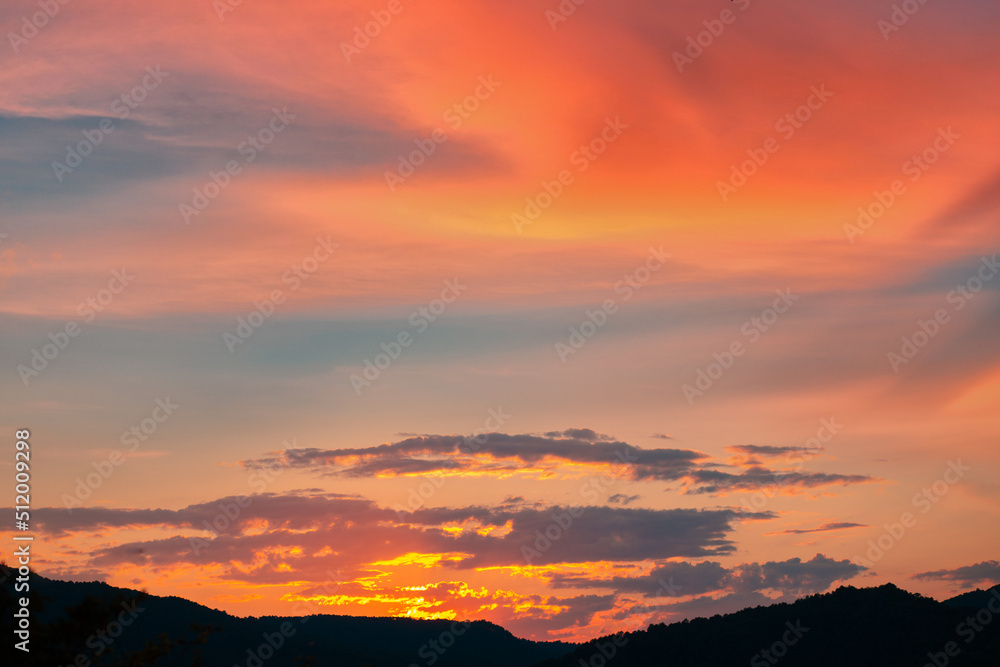 Dramatic summer golden sunset in the sky over the mountains silhouette. Copy space