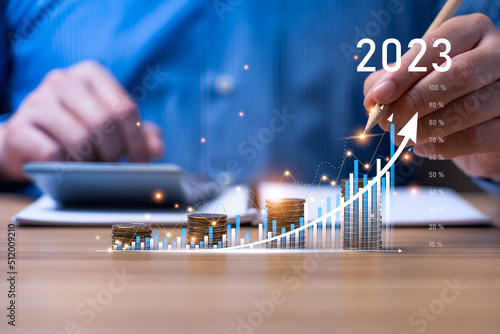 Businessman planning 2023 business growth on desk with virtual hologram chart graph. Calculate income and profit on investments and an increase in the indicators of positive growth, Return on Stocks