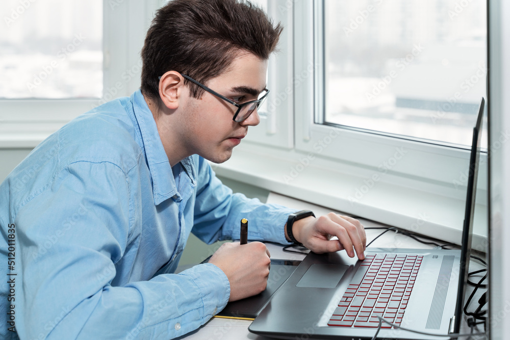 Fototapeta premium young male designer working on a professional graphics tablet with a pen