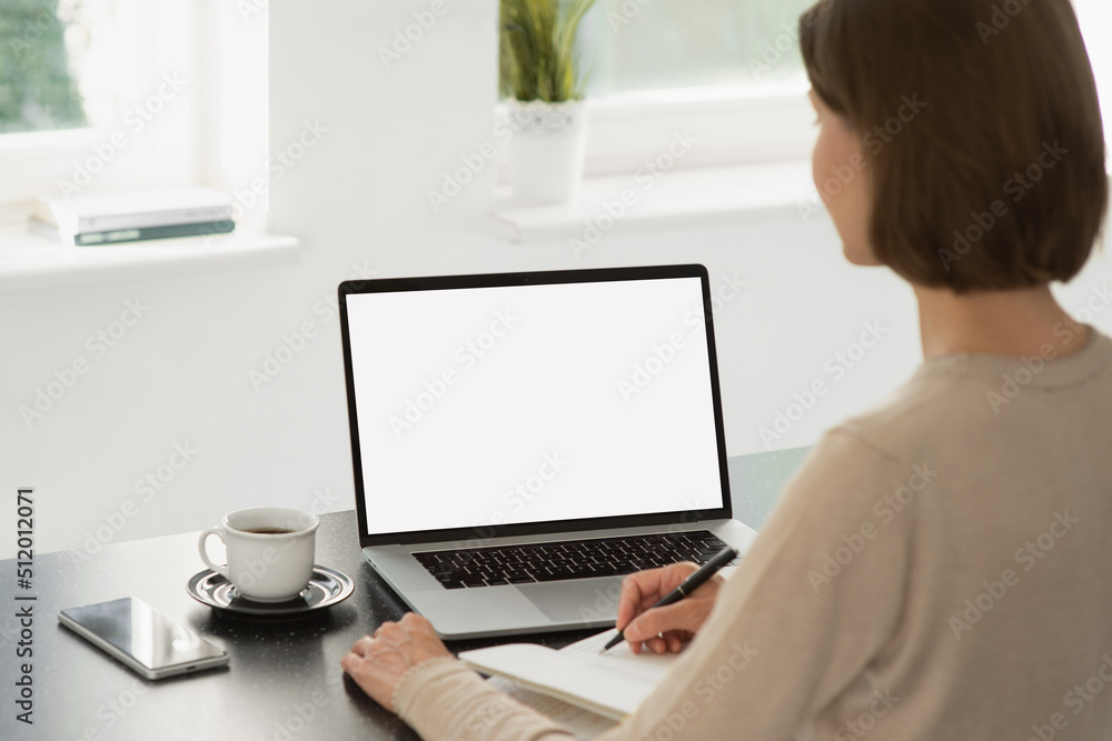 Young woman using laptop computer with white mockup screen at home. Business woman working in office. Freelance, student lifestyle, e-learning, technology and online meeting concept Young woman using laptop computer with white mockup screen at home. Business woman working in office. Freelance, student lifestyle, e-learning, technology and online meeting concept