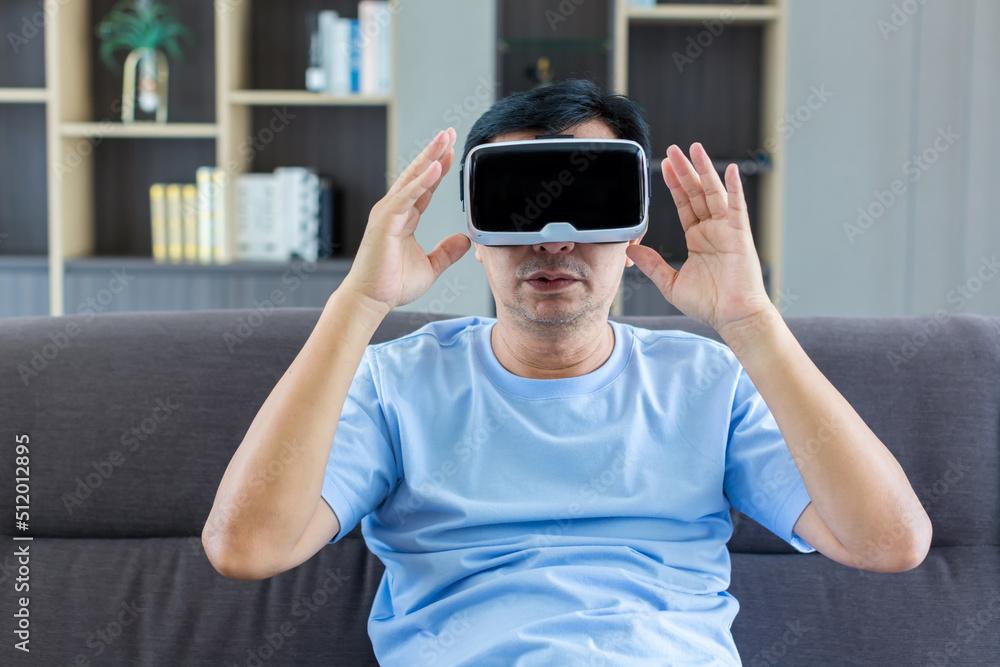 Dad using VR glasses at home for gaming or learning. Man in vr headsets experiencing Virtual reality on couch at home Dad using VR glasses at home for gaming or learning. Man in vr headsets experiencing Virtual reality on couch at home