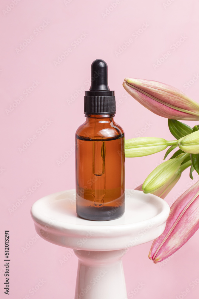 Glass dropper bottle on podium with lily flowers on pink background. Hyaluronic acid oil, serum with collagen and peptides skin care product. Cosmetic liquid mockup in bottle. Glass dropper bottle on podium with lily flowers on pink background. Hyaluronic acid oil, serum with collagen and peptides skin care product. Cosmetic liquid mockup in bottle.