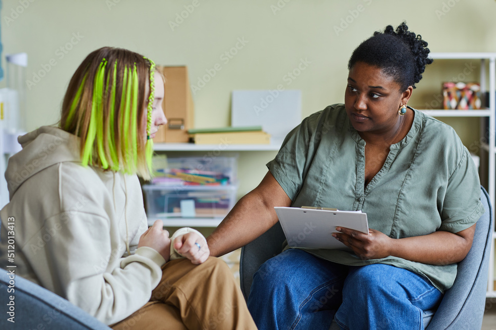 African female school psychologist supporting sad teenage girl during her difficult situation at school - obrazy, fototapety, plakaty 