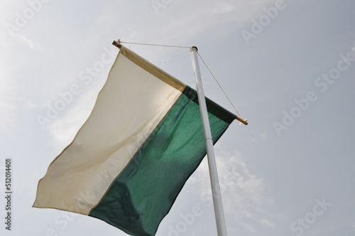   Sch  tzenfestflagge ist gehisst. Die Sch  tzenfestfahne weht im Wind vor blauen Himmel. Flaggenmast mit gr  nwei  en Banner.