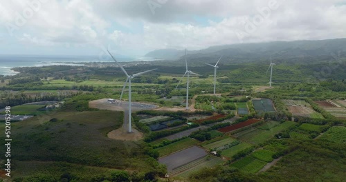 Flying along Wind power turbines on Kahuku Wind farm in Hawaii. Aerial view with mountains and ocean in the background photo
