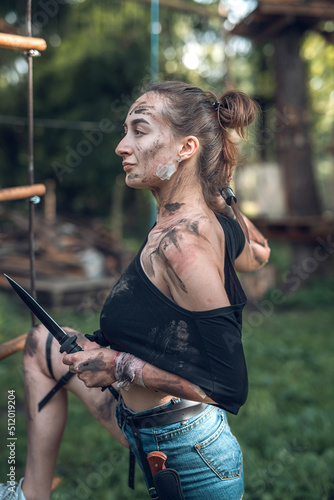 Foto Young woman holding sharp bayonet knife in forest