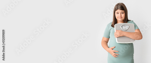 Sad overweight girl with measuring scales on light background with space for text photo