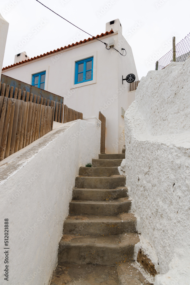 A narrow staircase leads up towards a white building surrounded by white walls