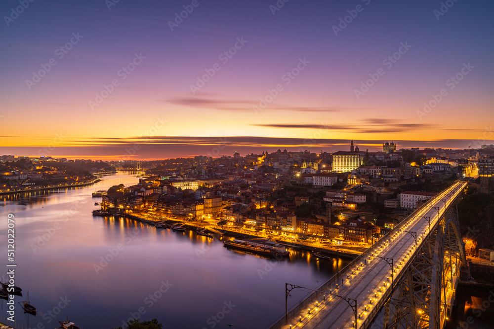 The cityscape of Porto with a bridge in the foreground at sunset and nightfall