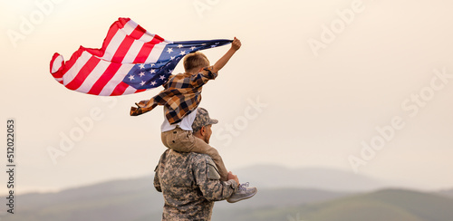 Foto Excited child sitting with american flag on shoulders of father reunited with fa