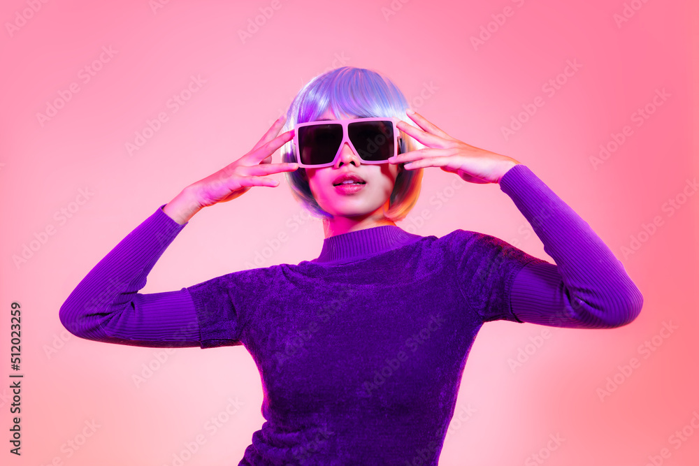 Young asian woman short blue milinium hairstyle wearing pink sunglasses posing on the red pastel and neon color background.