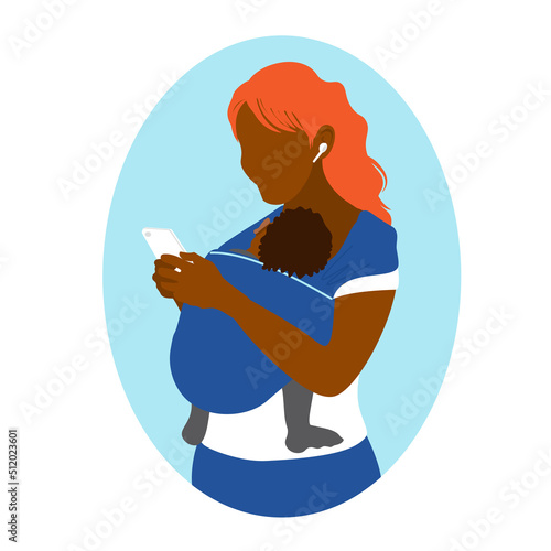 An African American woman uses a smartphone while holding a baby in a kangaroo bag. Wearing in a sling. Mother's free hands. Newborn laid back nursing care. 