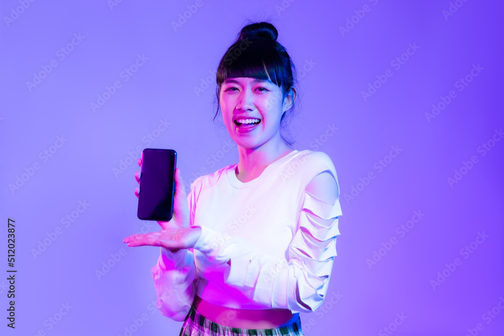 Young asian woman in white fashion sweatshirt using and holding and showing black screen smartphone on the purple background. Young asian woman in white fashion sweatshirt using and holding and showing black screen smartphone on the purple background.