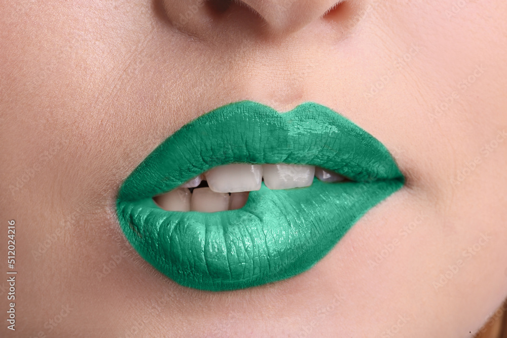 Fototapeta premium Beautiful young woman with makeup in mint colors biting her lip, closeup