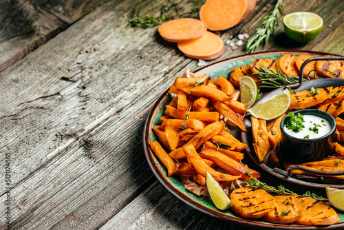 Set of homemade baked sweet potato fries with lime. Sweet potato fries with herbs on wooden background banner, menu, recipe place for text, top view