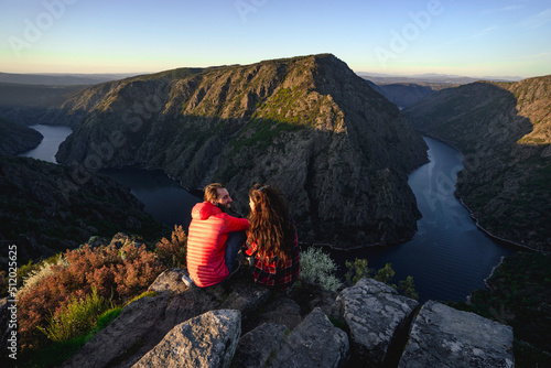 Couple sitting on rocks near Sil river in valley photo