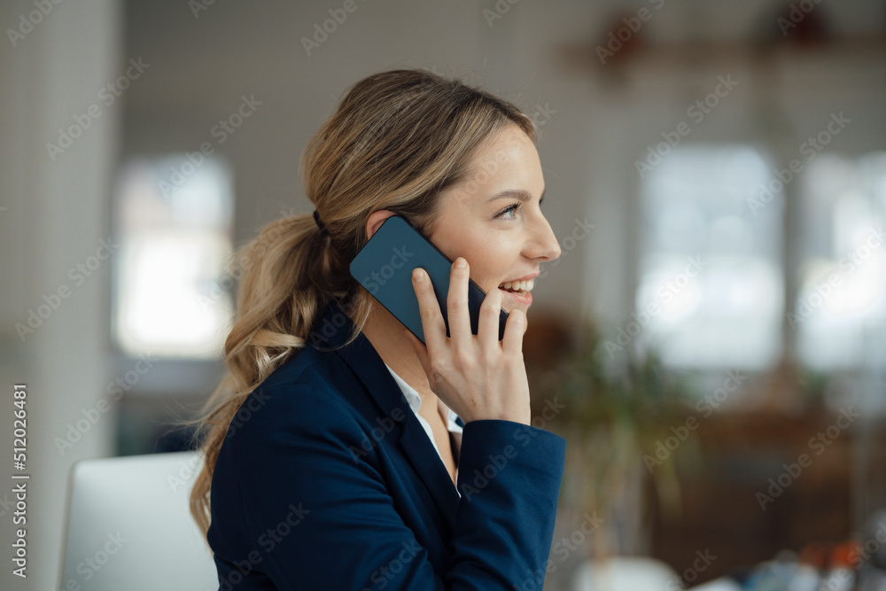 Happy businesswoman talking on smart phone in office Happy businesswoman talking on smart phone in office